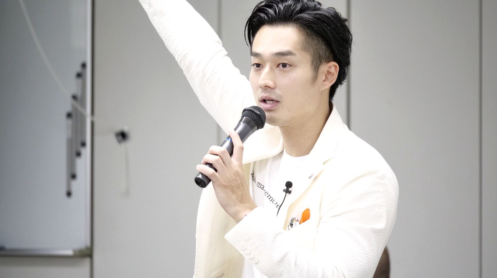 講演でマイクを持ち呼びかける代表